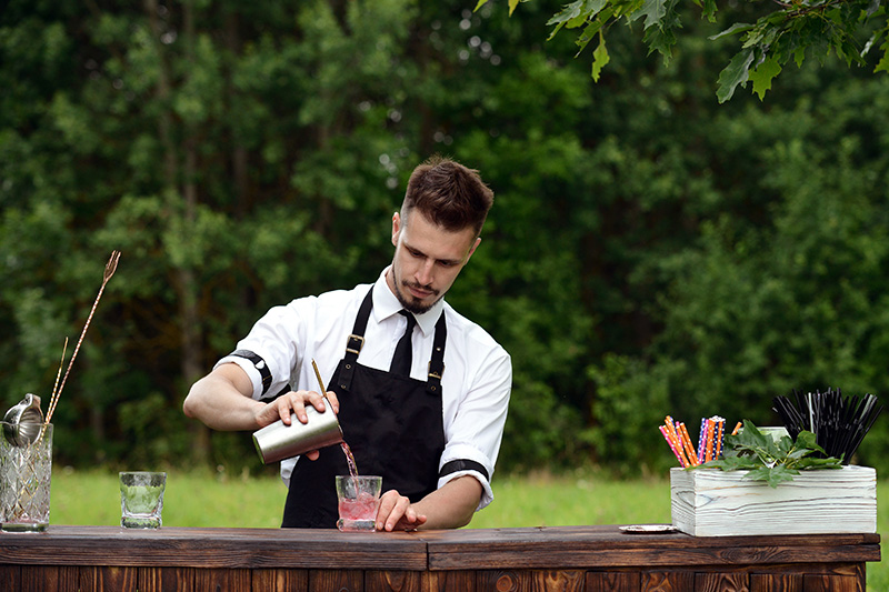 Residential Event Bartending Staff Residential event staff bartender prepares cocktails at an outdoor gathering.