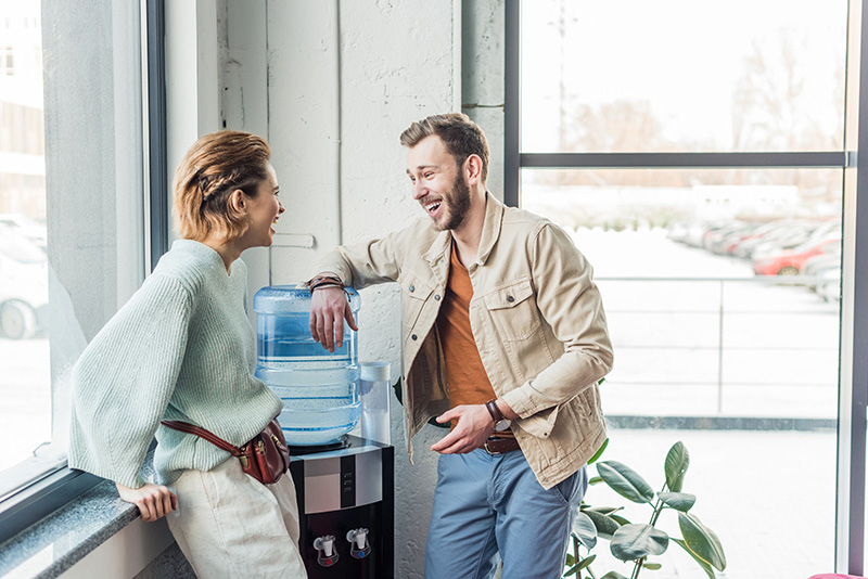 Casual businessman and woman talking and laughing in loft office 